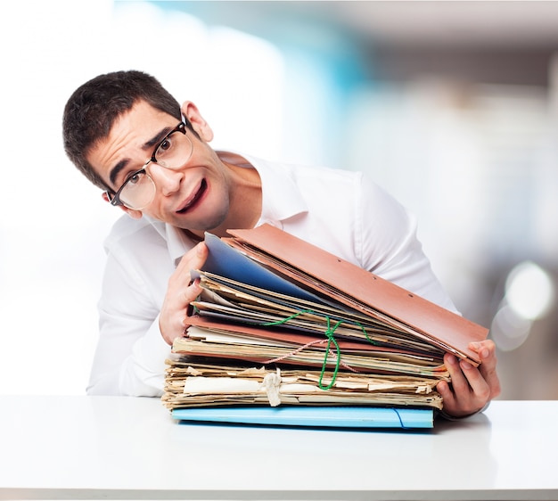 Stressed man looking at a mountain of folders