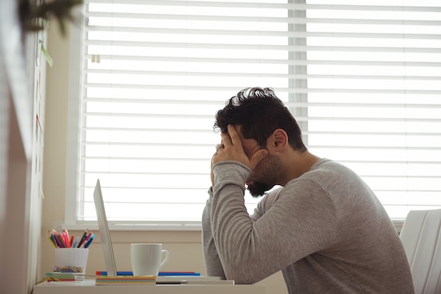 頭に手を置いて座っているストレスの多い男