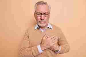Free photo stressed mature man touches chest suffers from heart attack