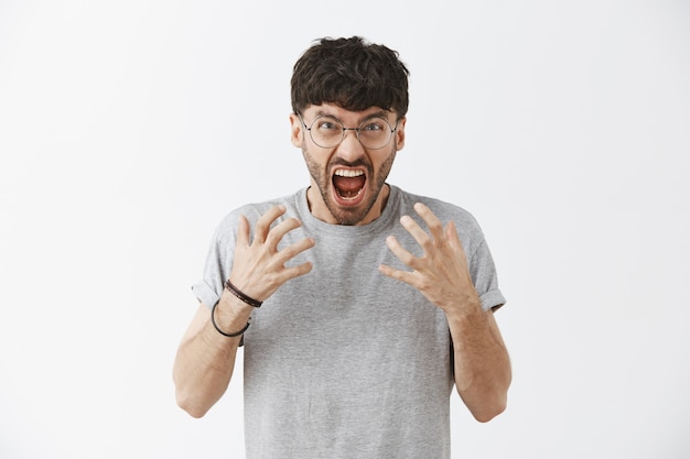 Stressed-out handsome guy posing against the white wall