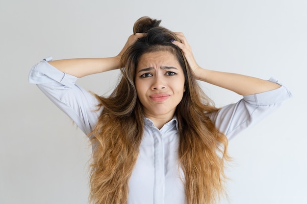 Free photo stressed pretty woman looking at camera and clutching head