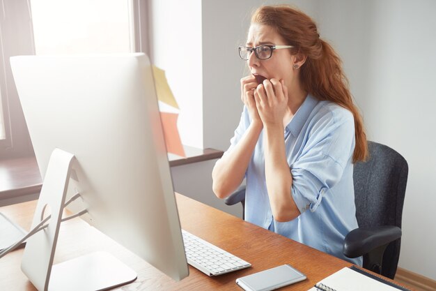 Stressed shocked businesswoman sitting at the table in front of computer