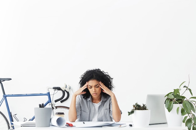 Stressed and unhappy African American student engineer squeezing her temples