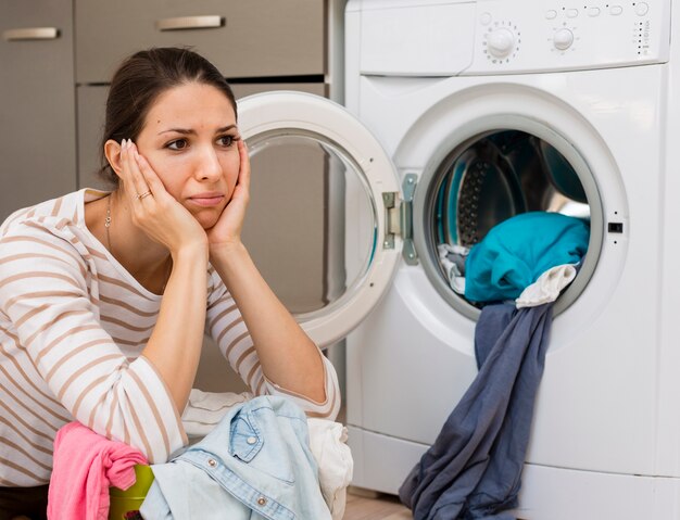 Stressed woman doing laundry medium shot