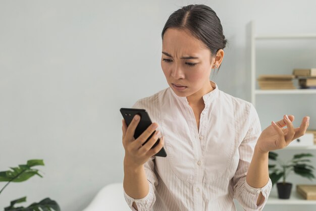 Stressed woman at office checking phone