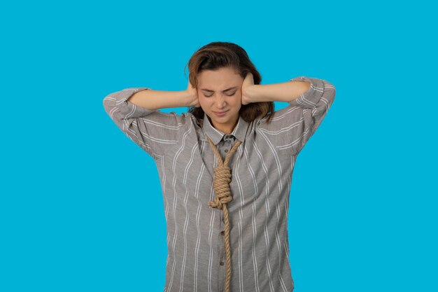 A stressed young adult hang a rope around her neck and put hands to her ear. High quality photo
