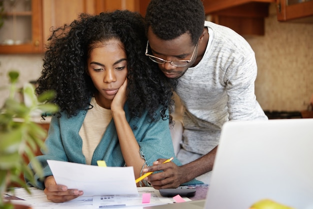 Stressed young African-American couple working through paperwork together