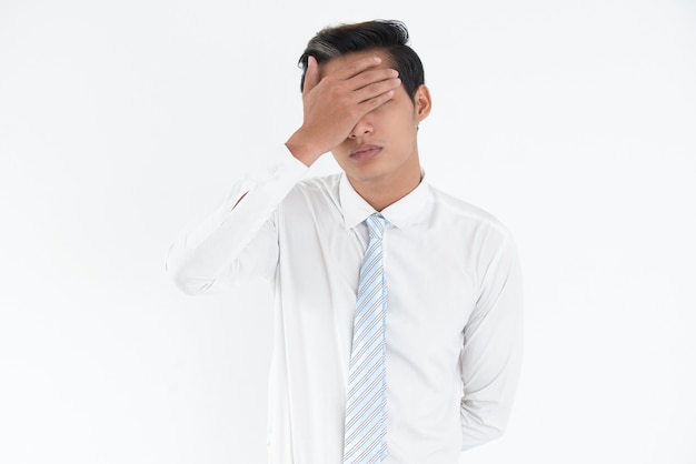 Stressed young Asian businessman covering eyes