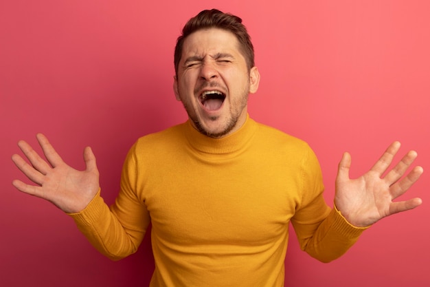 Free photo stressed young blonde handsome man showing empty hands screaming with closed eyes