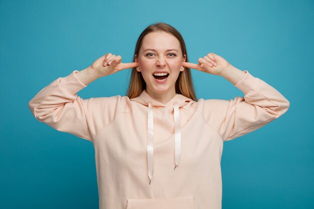 Stressed young blonde woman keeping fingers in ears 