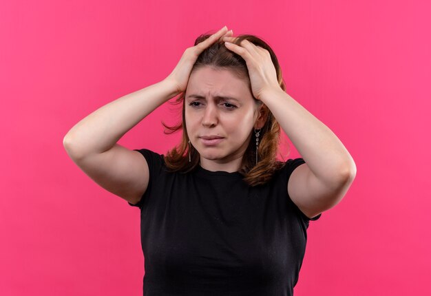Stressed young casual woman with hands on head on isolated pink wall