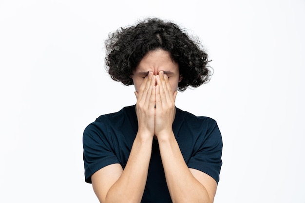 Free photo stressed young handsome man keeping hands on face with closed eyes isolated on white background