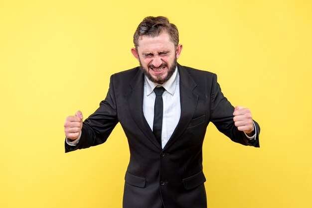 Stressed young man closing his eyes and cleching his fists on yellow