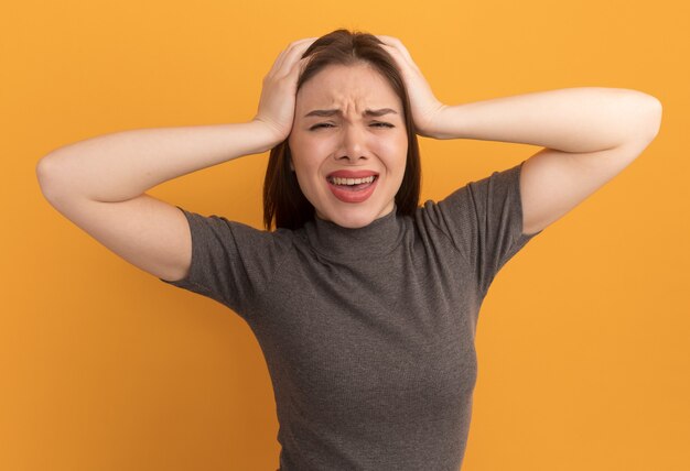 Stressed young pretty woman putting hands on head 