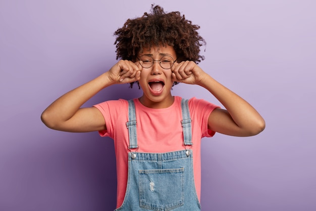 Stressed young woman with an afro posing in overalls