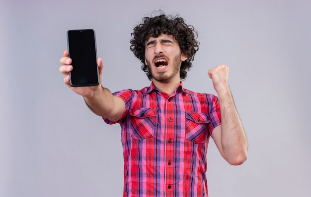 A stressful handsome man with curly hair in checked shirt showing blank space of mobile phone 