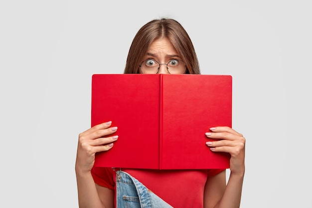 Stressful shocked student aftraids of answering, hides behind book