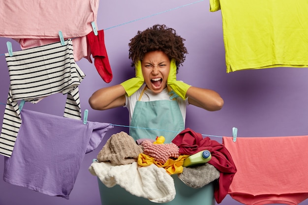 Free photo stressful young woman with an afro posing with laundry in overalls