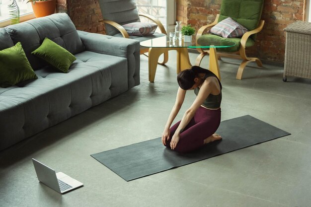 Stretching. Sporty beautiful young woman practicing yoga's asanas like professional at home