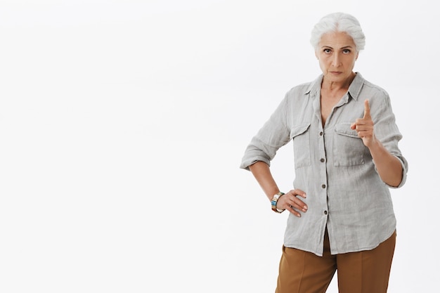 Strict and bossy granny scolding person, shaking finger angry with disapproval