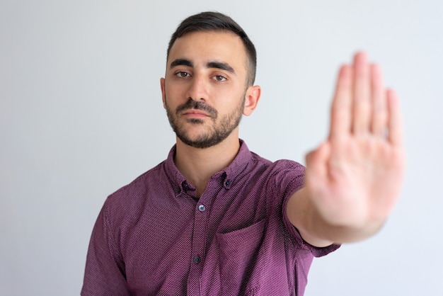 Strict businessman in casual gesturing stop