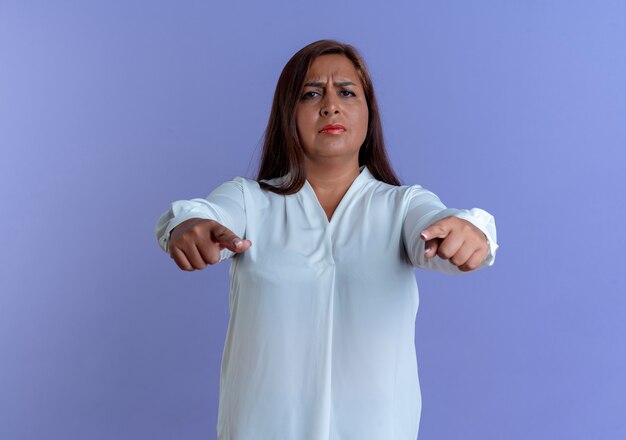 Strict casual caucasian middle-aged woman showing you gesture isolated on blue wall
