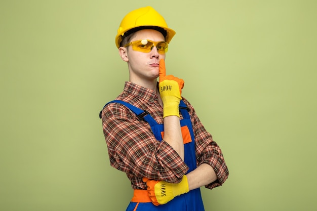 Strict crossing hands showing silence gesture young male builder wearing uniform and gloves with glasses 