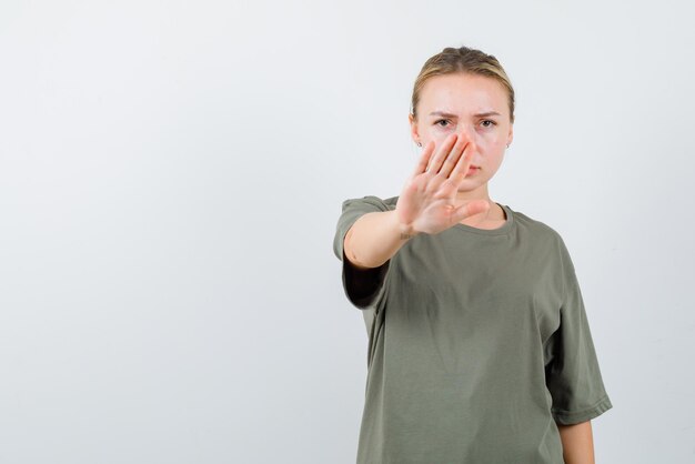 Strict girl showing stop hand gesture on white background