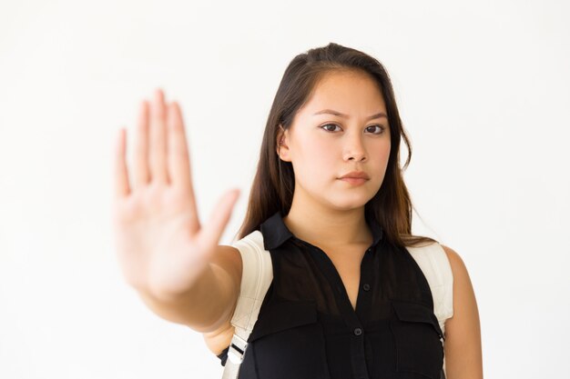 Строгая серьезная девочка-подросток делает жест рукой стоп