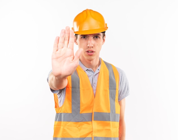 Strict young builder man in uniform showing stop gesture 