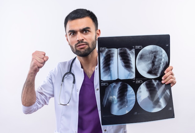 Strict young male doctor wearing stethoscope medical gown holding x-ray on isolated white background