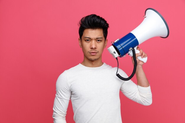 Strict young man holding speaker 