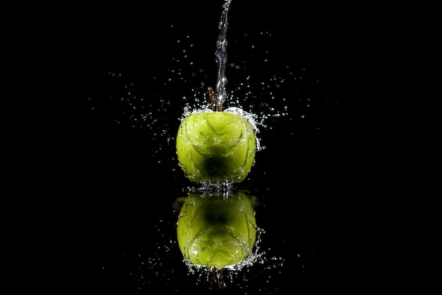 Strim of water pours on green apple on black background