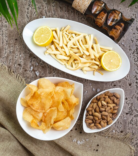 String cheese with lemon in a bowl served with potato chips and pistachios