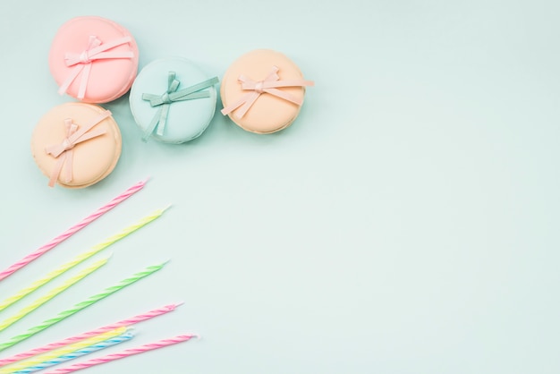 Striped candles and macarons with bow on white background