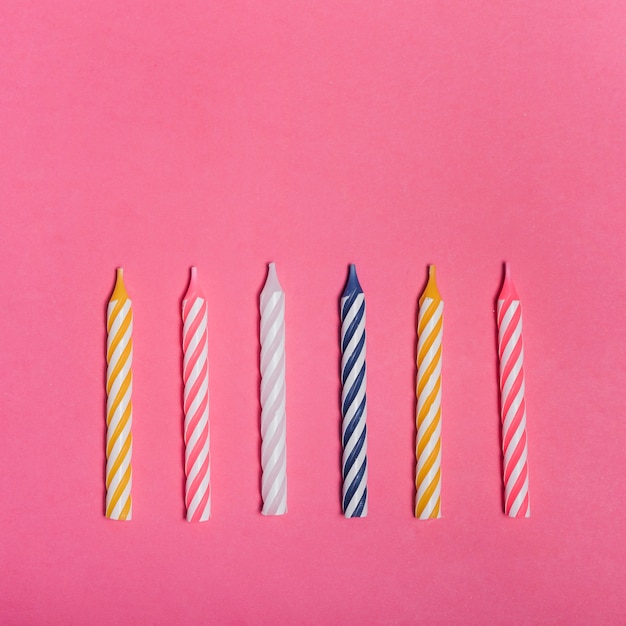 Free photo striped colorful candles on pink background
