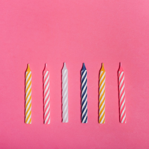 Striped colorful candles on pink background