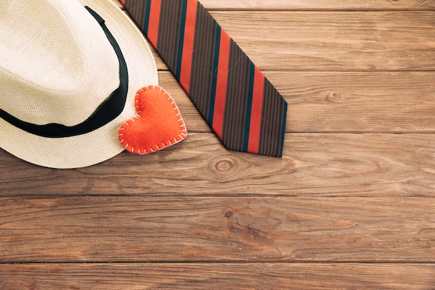 Striped tie near hat and heart on board