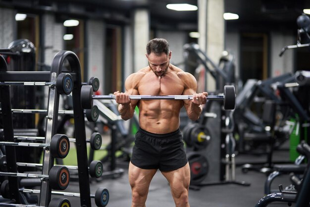 Strong athlete lifting barbell exercising in gym