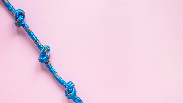 Бесплатное фото Сильный синий узел веревки на розовом фоне пространства копии