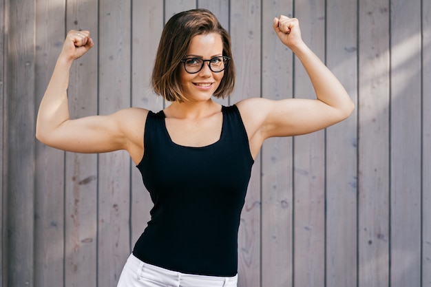 Premium Photo Strong Fitness Woman With Short Hair Dressed Casual Demonstrates Her Biceps Outdoor