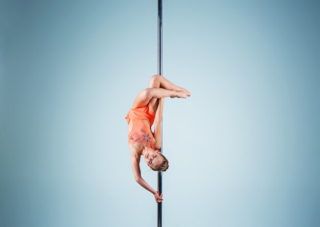 The strong and graceful young girl performing acrobatic exercises on pylon