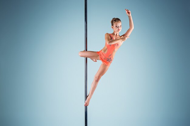 The strong and graceful young girl performing acrobatic exercises on pylon