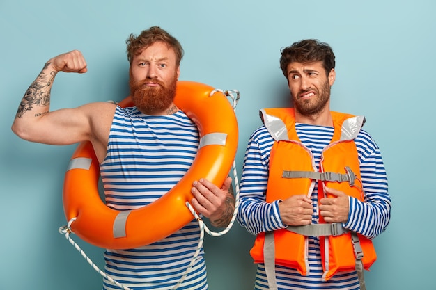 Free photo strong guys posing at the beach with lifejacket and lifebuoy