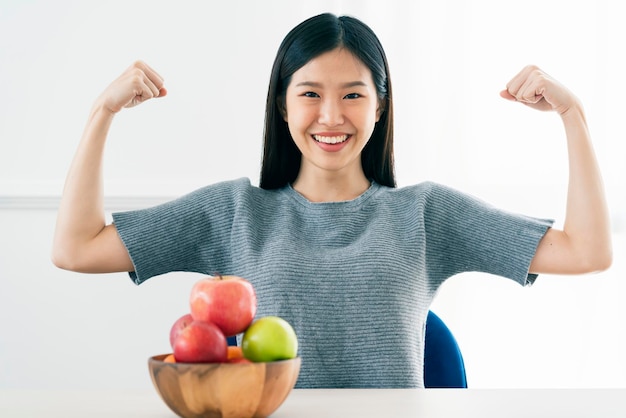 건강하고 아름다운 아시아 여성의 손은 건강한 음식 다이어트 아이디어 개념을 가지고 행동에 적합하고 확고한 포즈를 취하는 신선한 과일 사과를 보여줍니다.