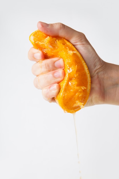 Strong human hand squeezing orange half for juice