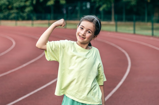 Free photo strong little girl posing outdoors showing their muscles