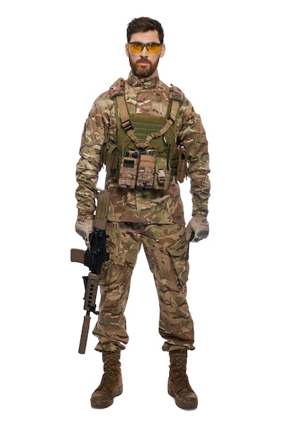 Strong male caucasian military soldier with rifle standing in studio front view of handsome bearded