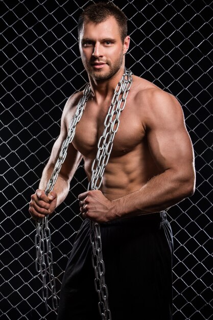 Strong man on fence with chains