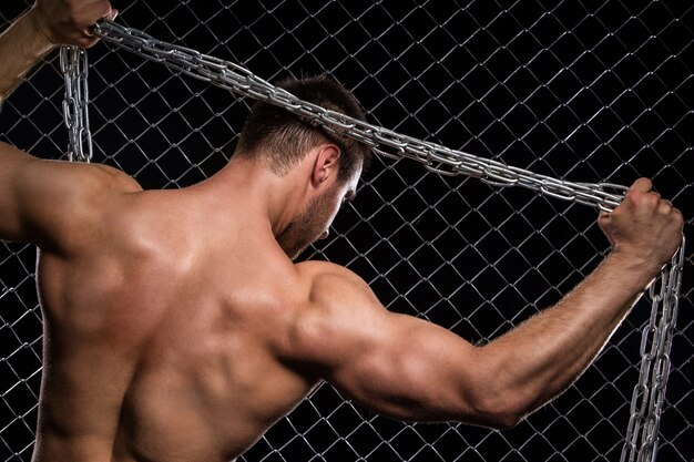 Strong man on fence with chains